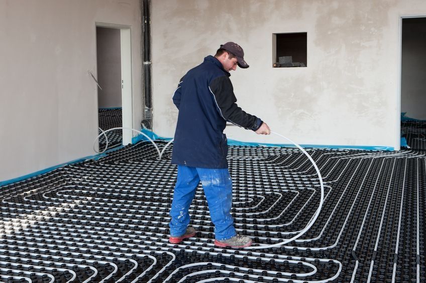 Un hombre está trabajando en un sistema de calefacción por suelo radiante.