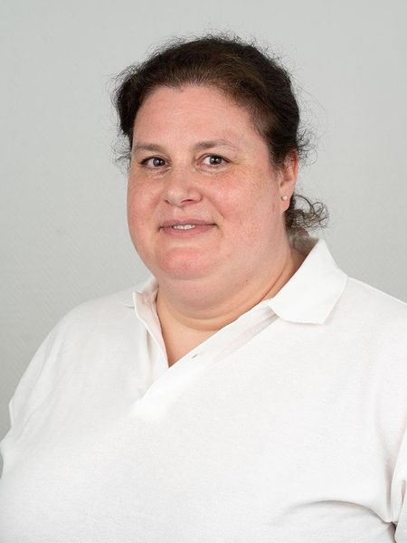 Eine Frau trägt ein weißes Hemd und lächelt in die Kamera.