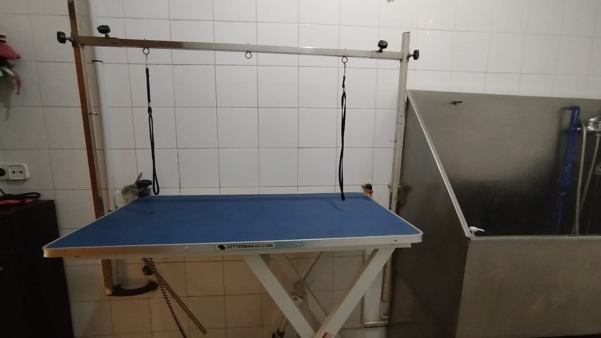 Una mesa azul en un baño al lado de una bañera de acero inoxidable.