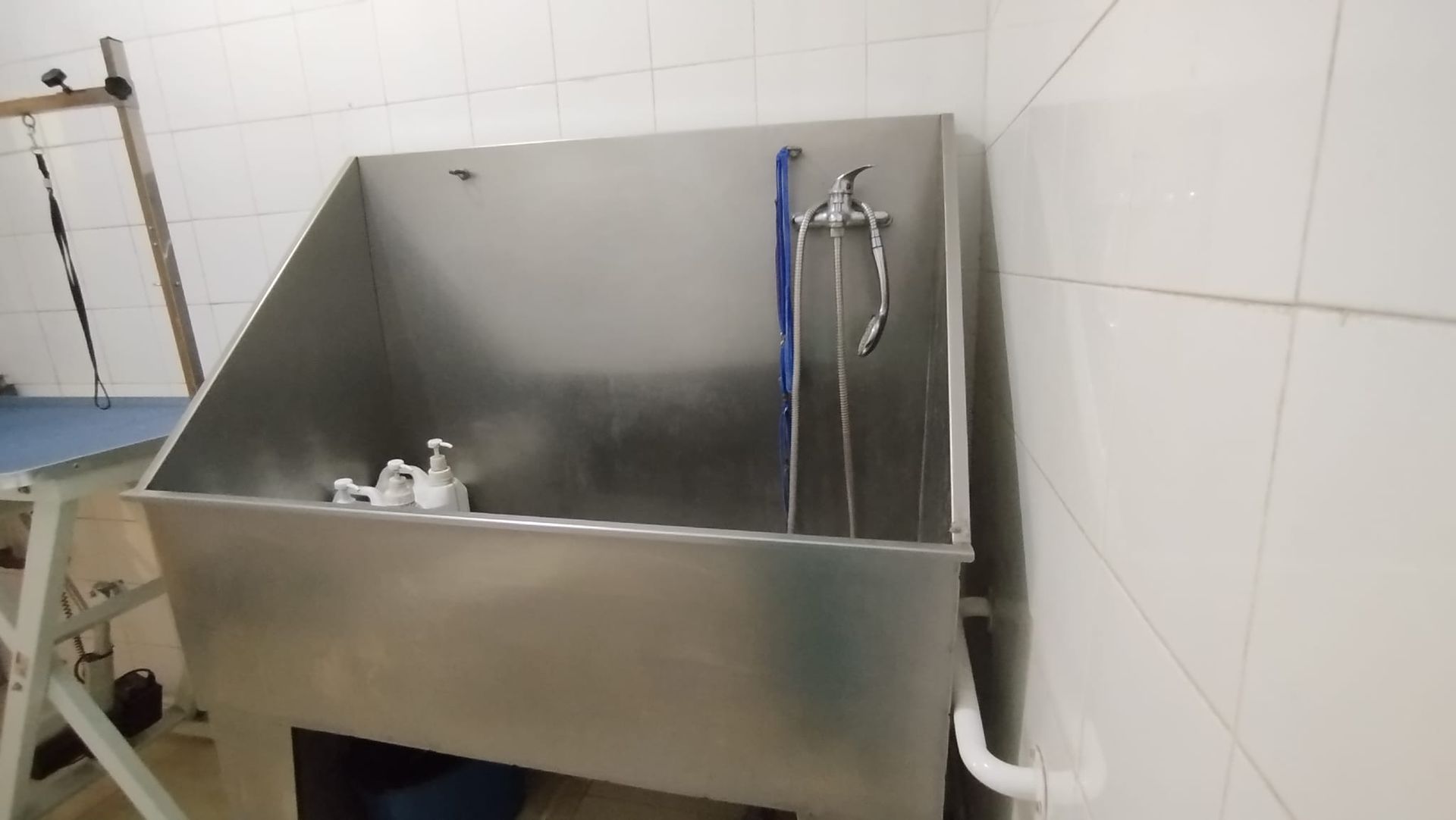 Un lavabo de acero inoxidable con ducha adjunta en un baño.