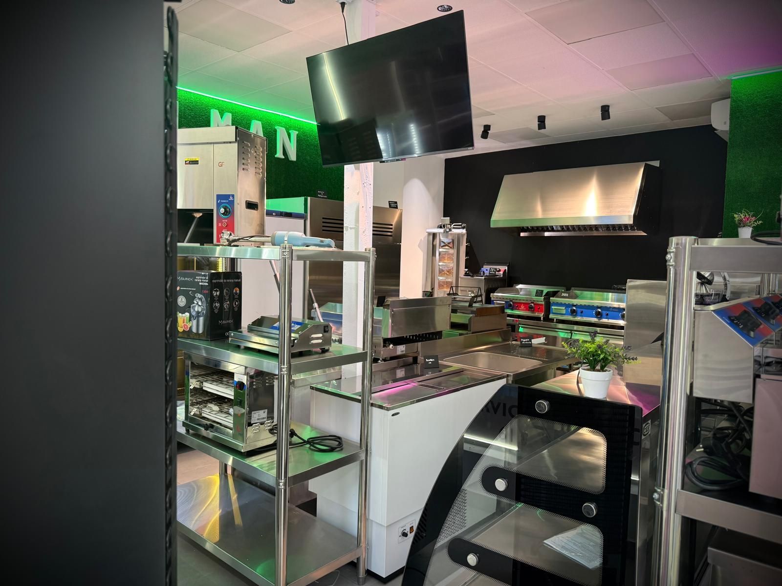 Diseño de cocina moderna con isla blanca, gabinetes negros, electrodomésticos de acero inoxidable e iluminación ambiental de color verde brillante.