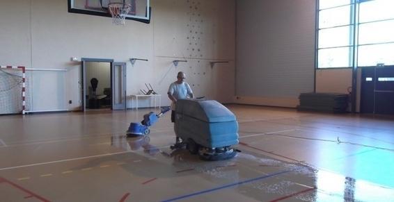 Professionnel utilisant une monobrosse pour nettoyer le sol d'un gymnase