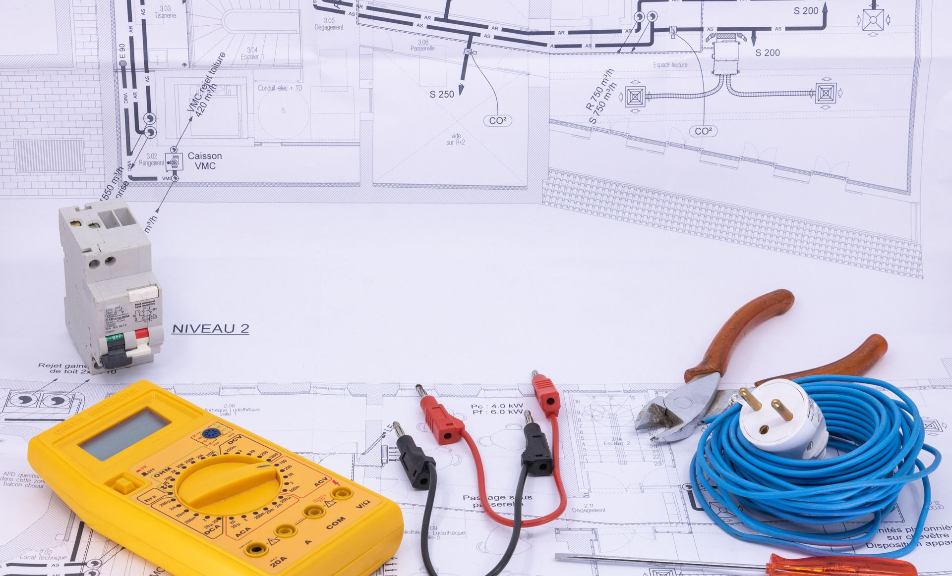 Outils de test électrique figurant sur les plans : multimètre, sondes, testeur de prises et câble enroulé.