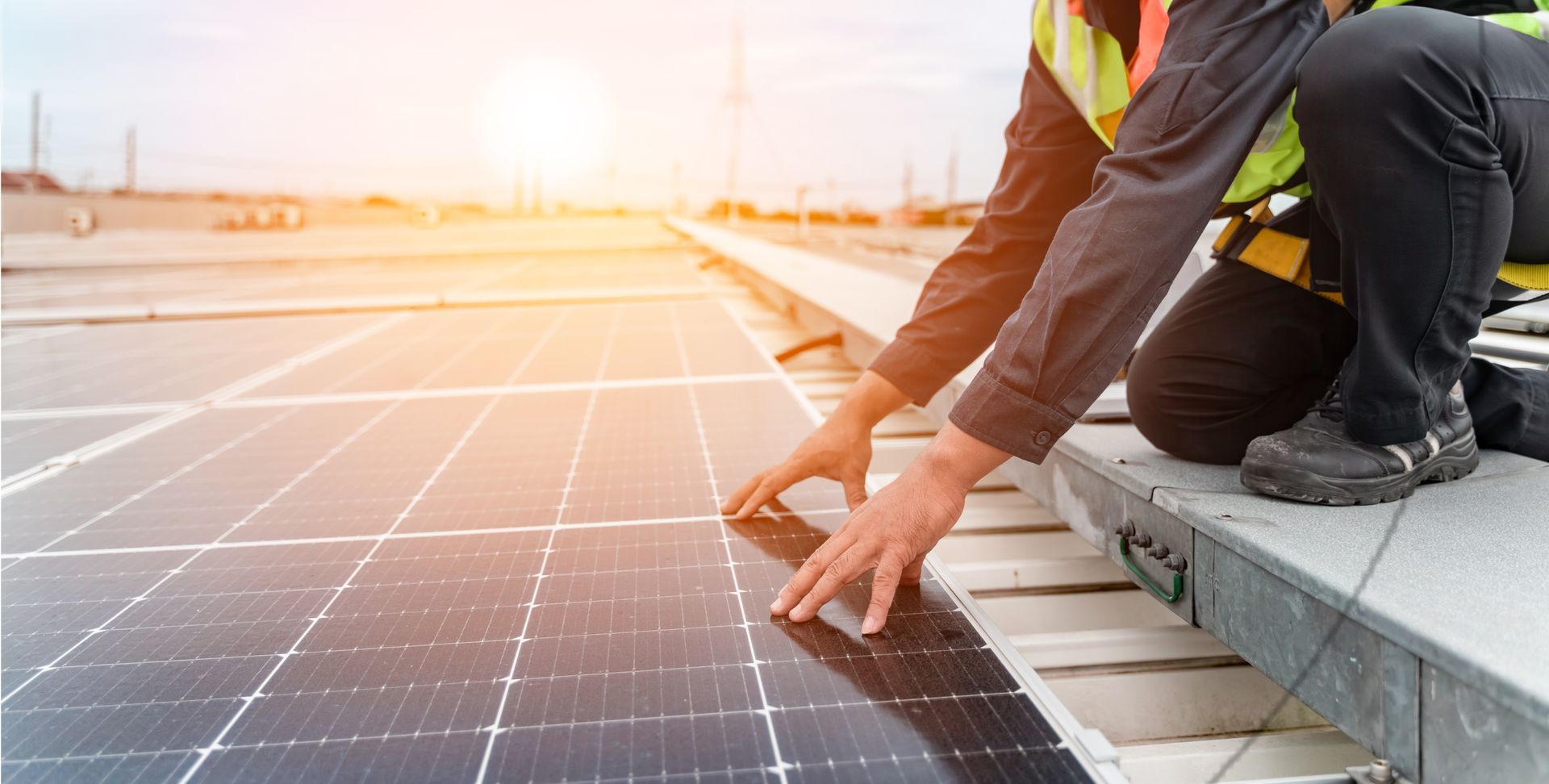 Des ouvriers installent des panneaux solaires sur un toit au lever du soleil