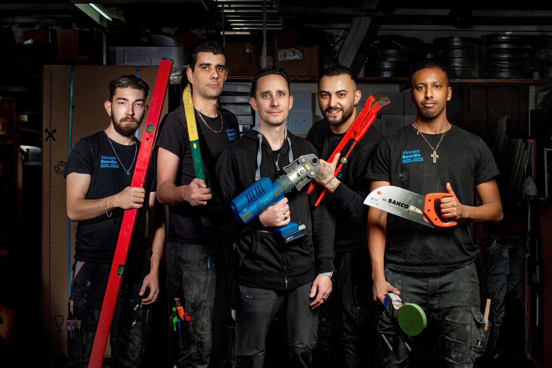 Un groupe d'hommes se tiennent les uns à côté des autres, tenant des outils | Vincent Bourdin Sàrl