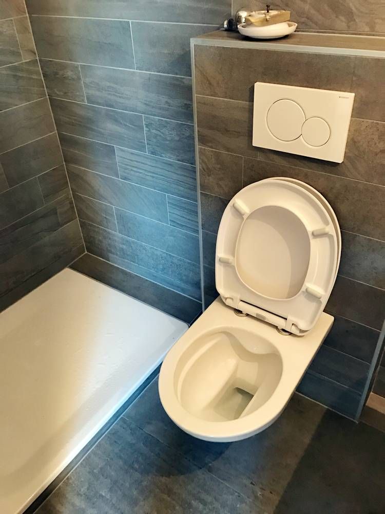 Une toilette est située dans une salle de bain à côté d'une baignoire | Vincent Bourdin Sàrl