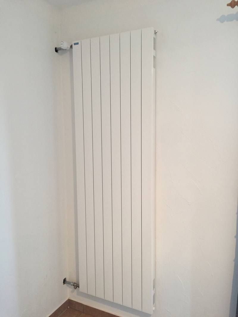 Un radiateur blanc est accroché sur un mur blanc dans une pièce | Vincent Bourdin Sàrl