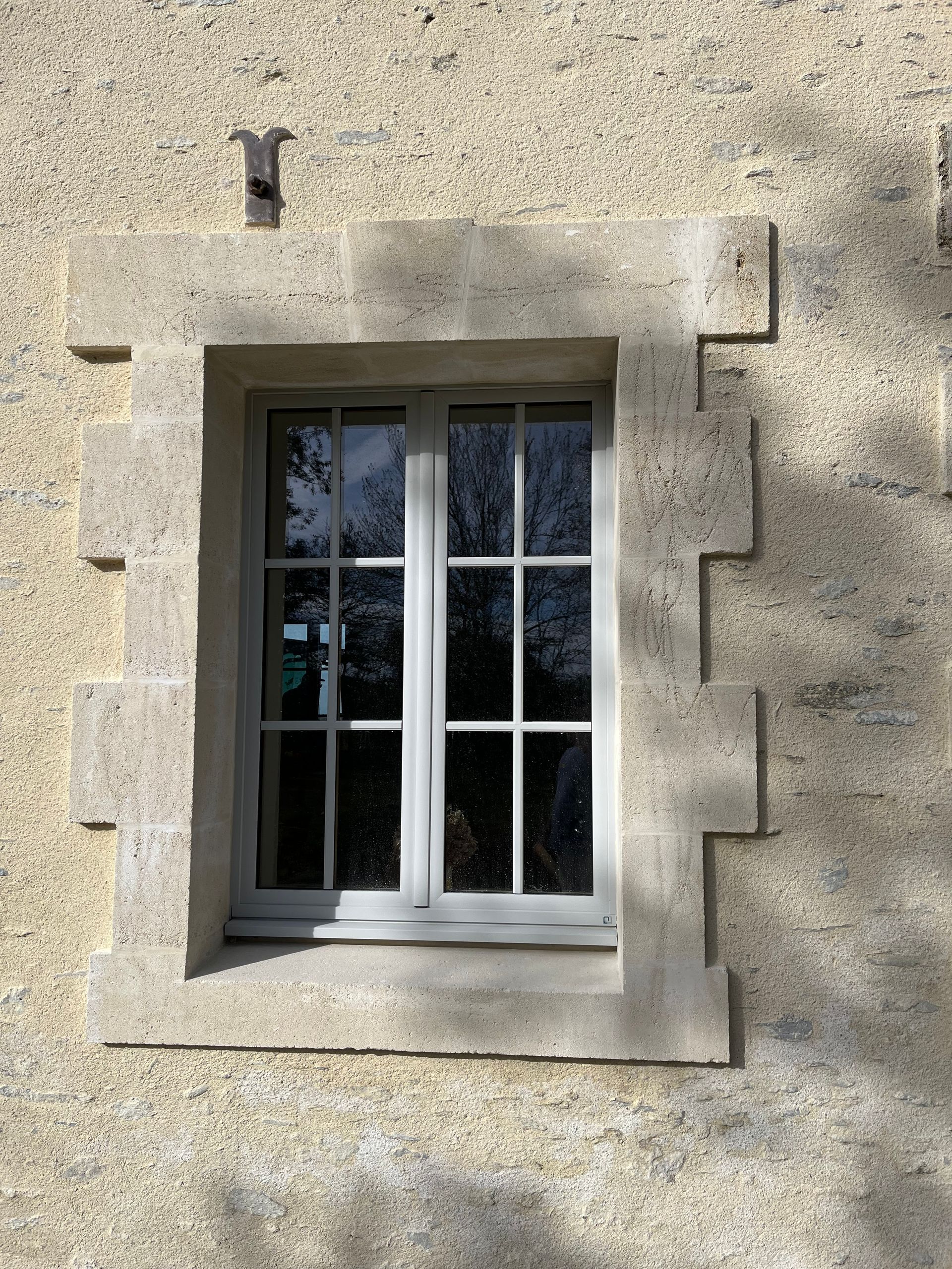 Grande fenêtre entourée de pierres de taille.
