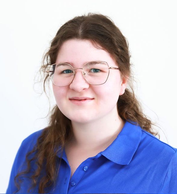 Eine Frau mit Brille und blauem Hemd lächelt in die Kamera.