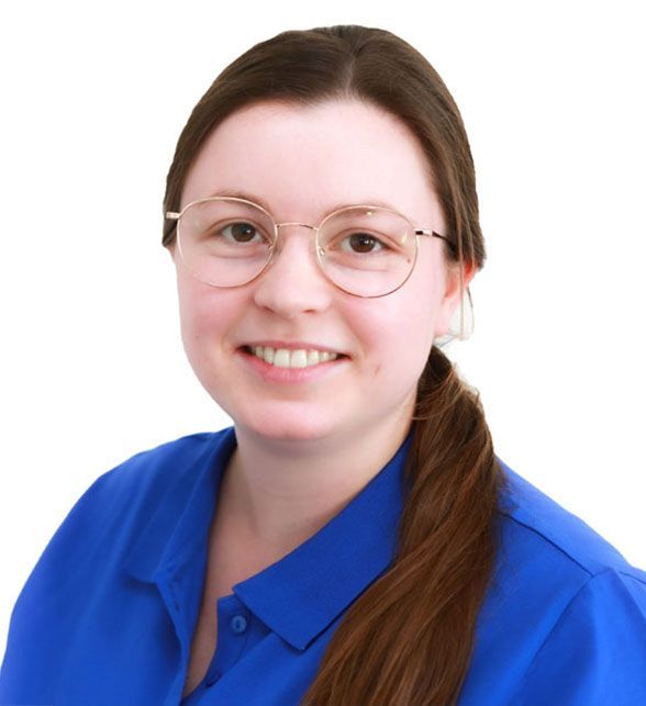 Eine Frau mit Brille und blauem Hemd lächelt in die Kamera