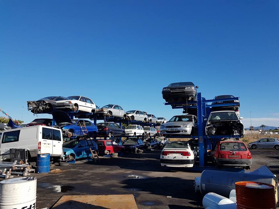 Muchos coches están apilados uno encima del otro en un estacionamiento.