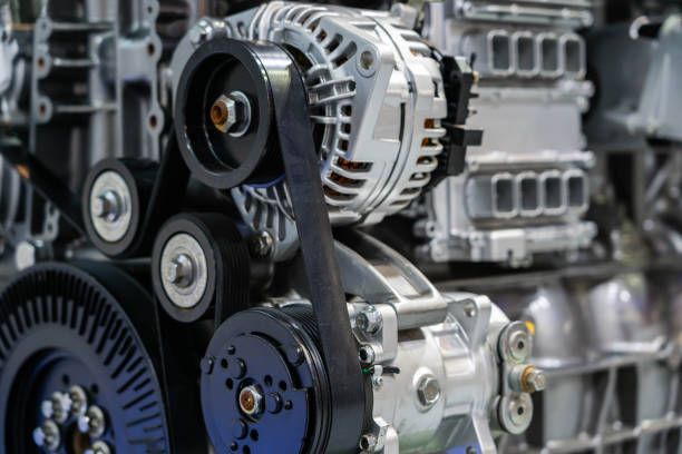 Um close de um motor de carro com correias e polias.