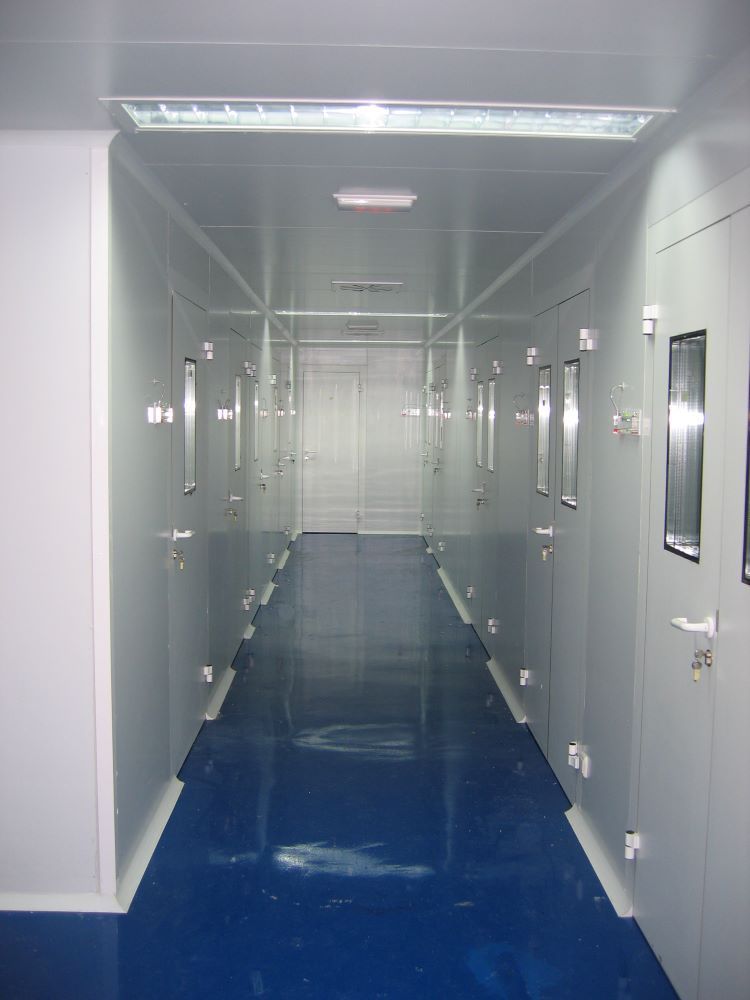 Un largo pasillo con pisos azules y paredes blancas.