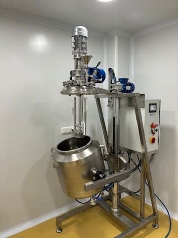 En una habitación hay un mezclador grande de acero inoxidable.