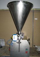 Una máquina llenadora de acero inoxidable está colocada encima de una mesa de madera.