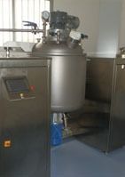 Un gran tanque de acero inoxidable está junto a una máquina en una habitación.