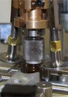 Una máquina está presionando una botella sobre una mesa.