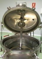 Un tanque de acero inoxidable con la tapa abierta y una manguera que sale de él.