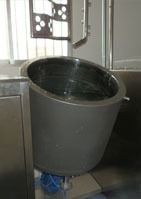 Un recipiente grande de acero inoxidable está junto a una batidora en una cocina.