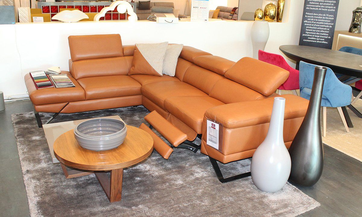 Salon aménagé avec canapé d'angle en cuir marron en mode relax, vase et table basse