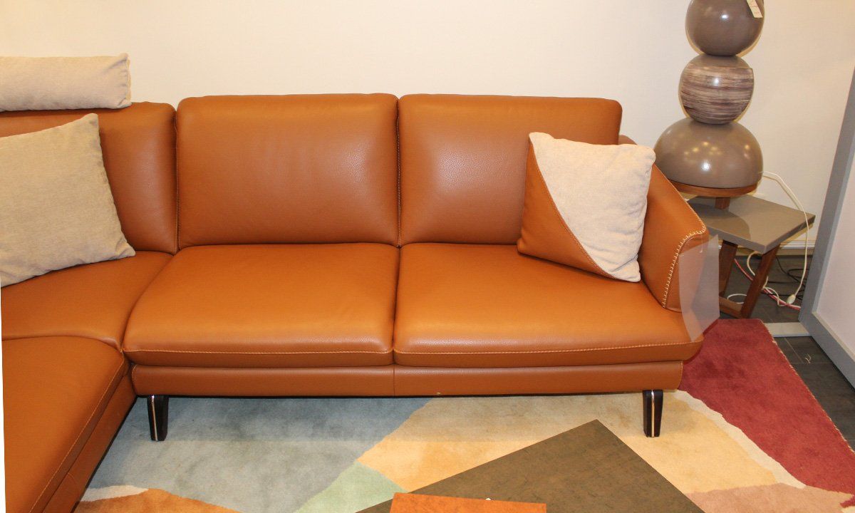 Oreiller marron et beige sur canapé d'angle en cuir marron