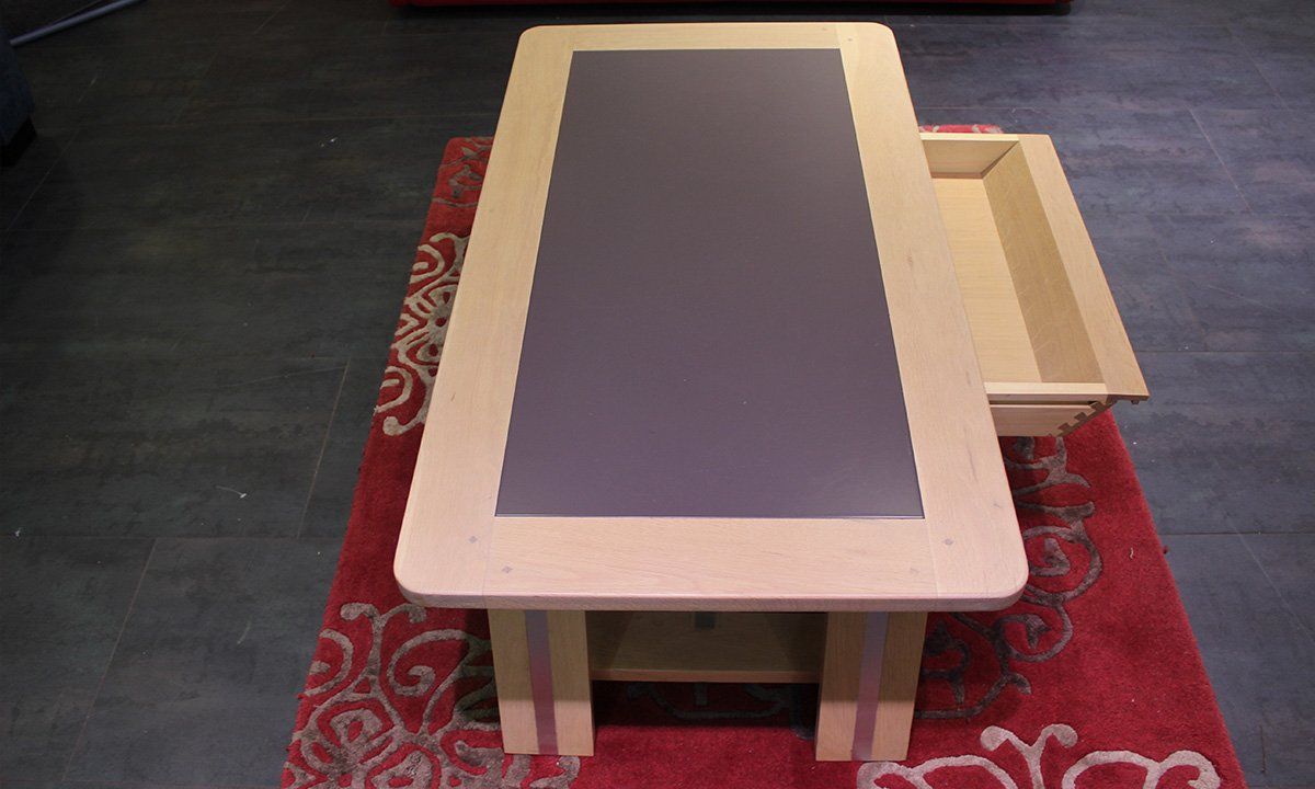 Table basse en bois et céramique avec tiroir ouvert sur tapis rouge avec formes de fleurs