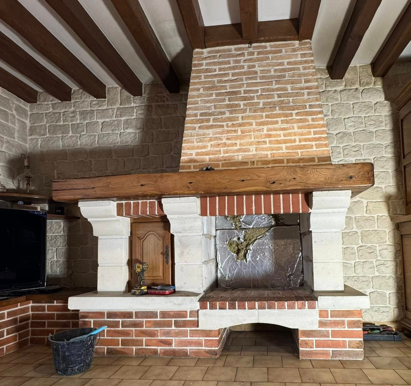 Cheminée en briques et en pierres avec un manteau et des murs d'enceinte en bois.