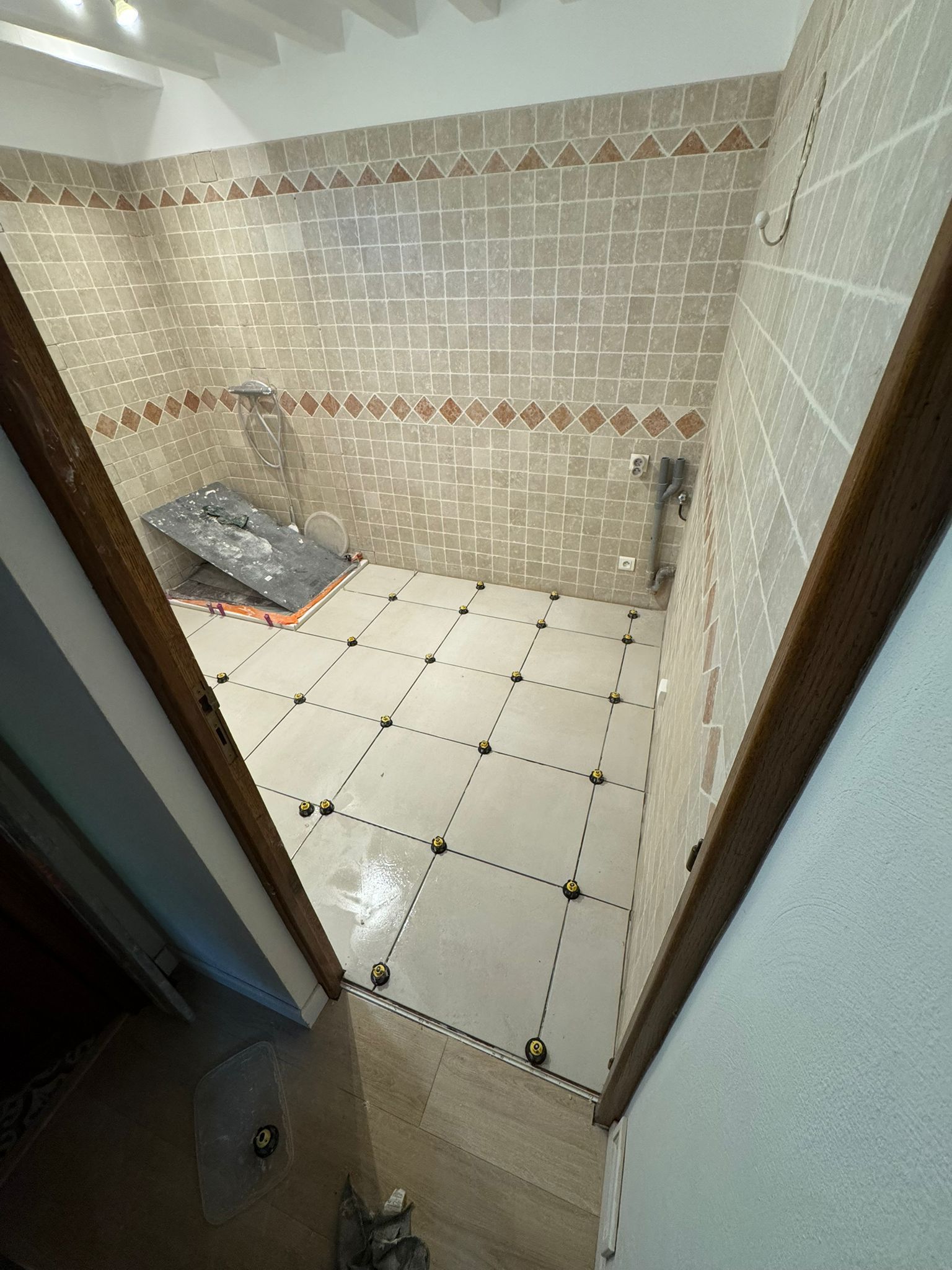 Salle de bains en construction avec nouveau carrelage au sol et aux murs.