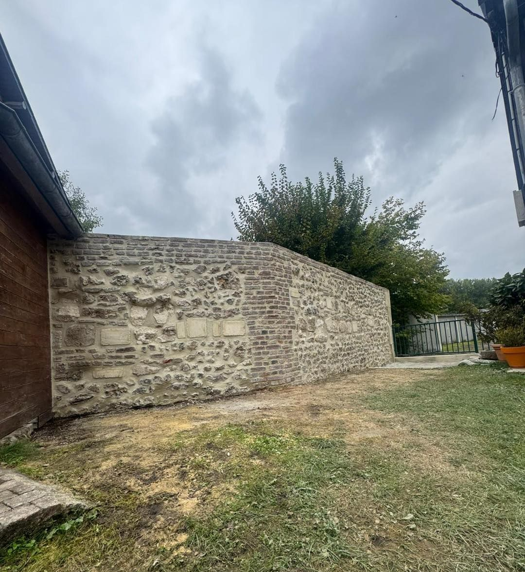 Mur en pierre, construction mêlant briques et rochers, à l'extérieur sous un ciel nuageux.