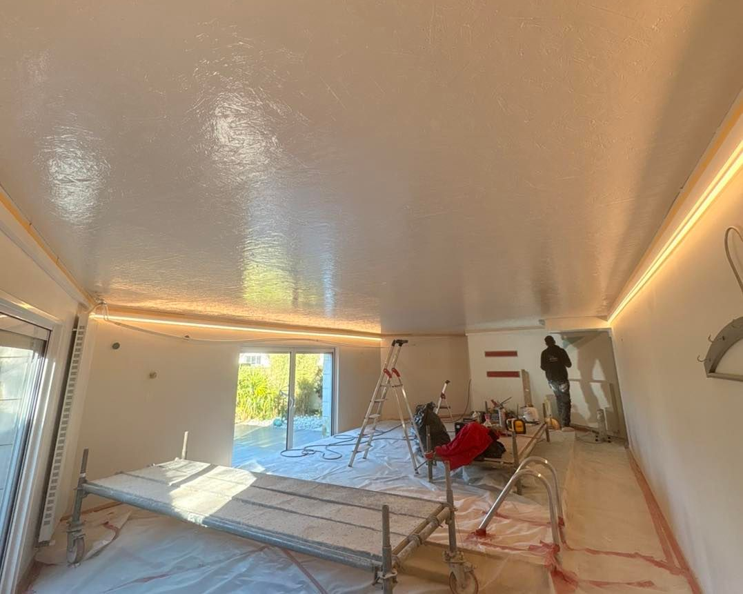 Pièce intérieure en rénovation, avec un plafond blanc brillant et humide.