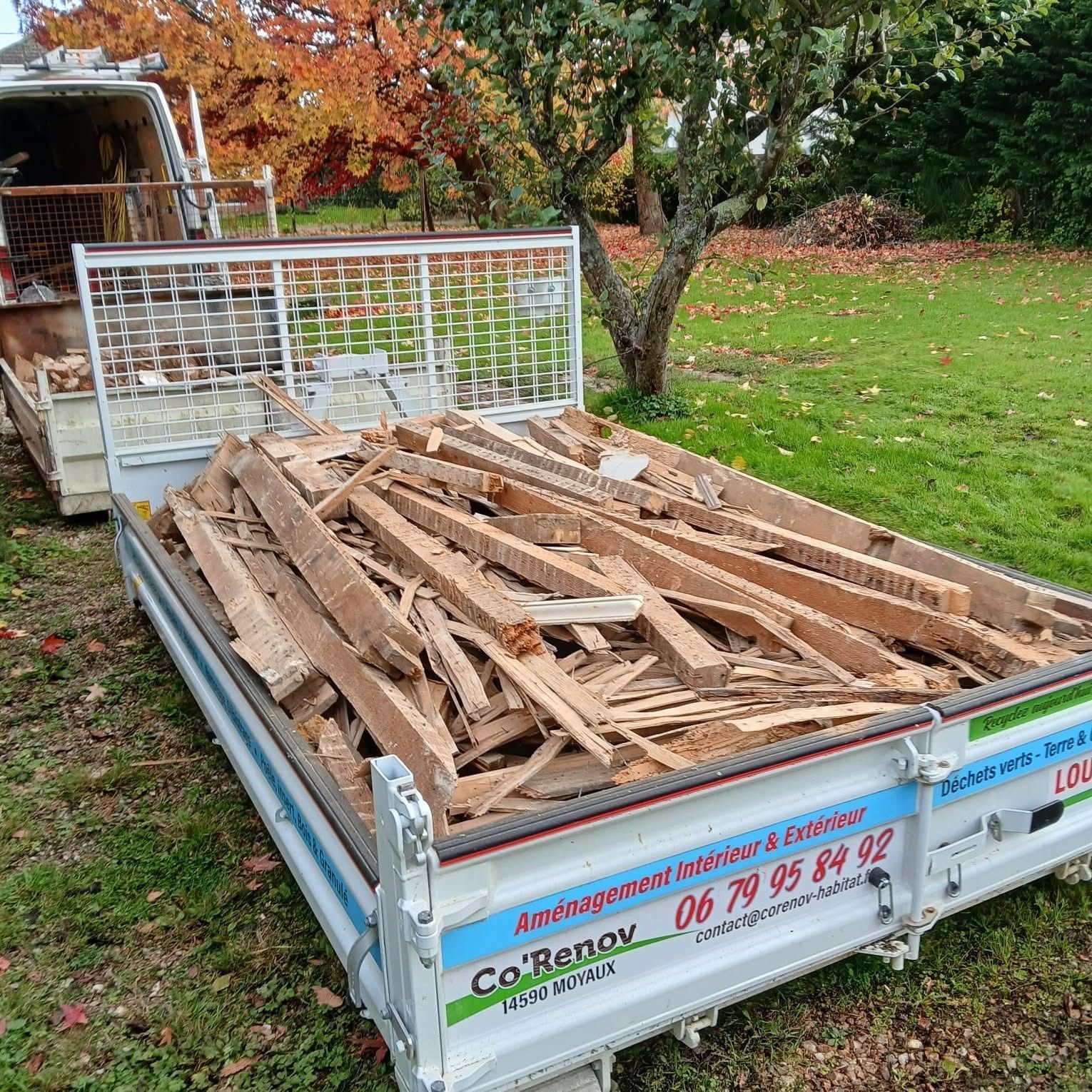 Petite remorque chargée de bois de récupération et de débris dans une cour herbeuse