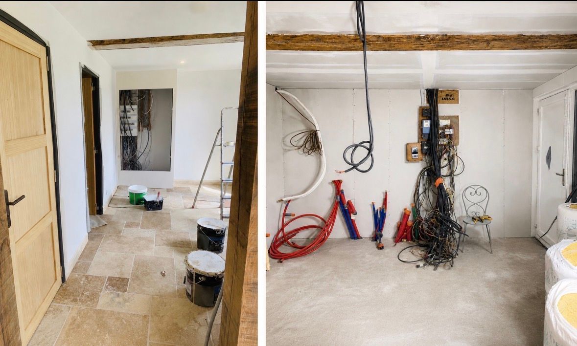 Travaux de rénovation en cours dans une pièce inachevée avec poutres apparentes, outils, câbles et pots de peinture au sol.