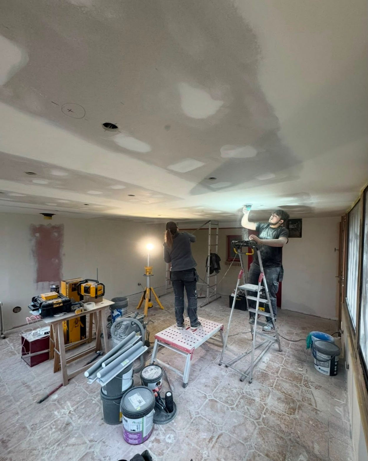 Intérieur d'une pièce en construction avec des murs en briques apparentes, un sol en béton.
