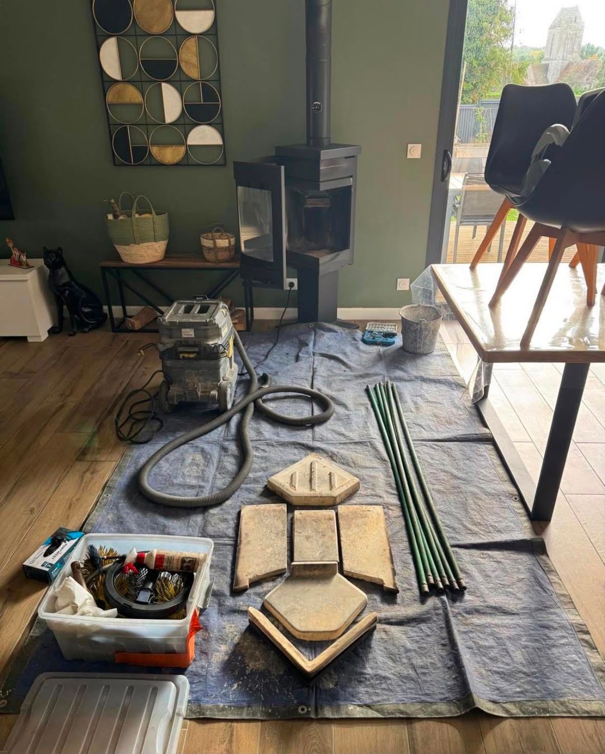 Sol du salon avec outils, carreaux de sol et tiges vertes regroupées, étalées sur une bâche pour un projet