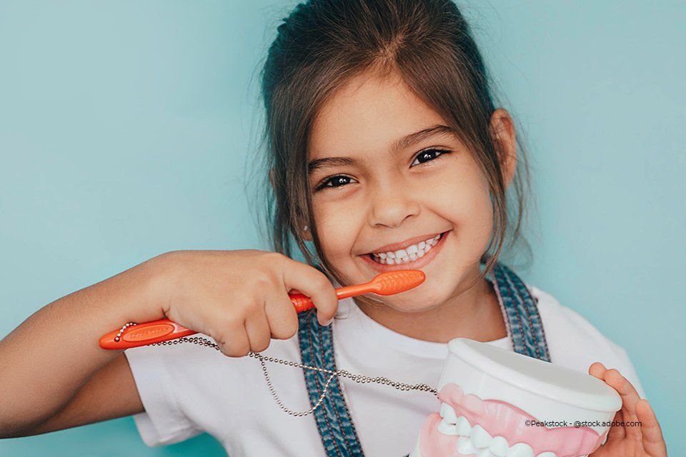 Lächelndes Kind hält Zahnbürste ins BIld