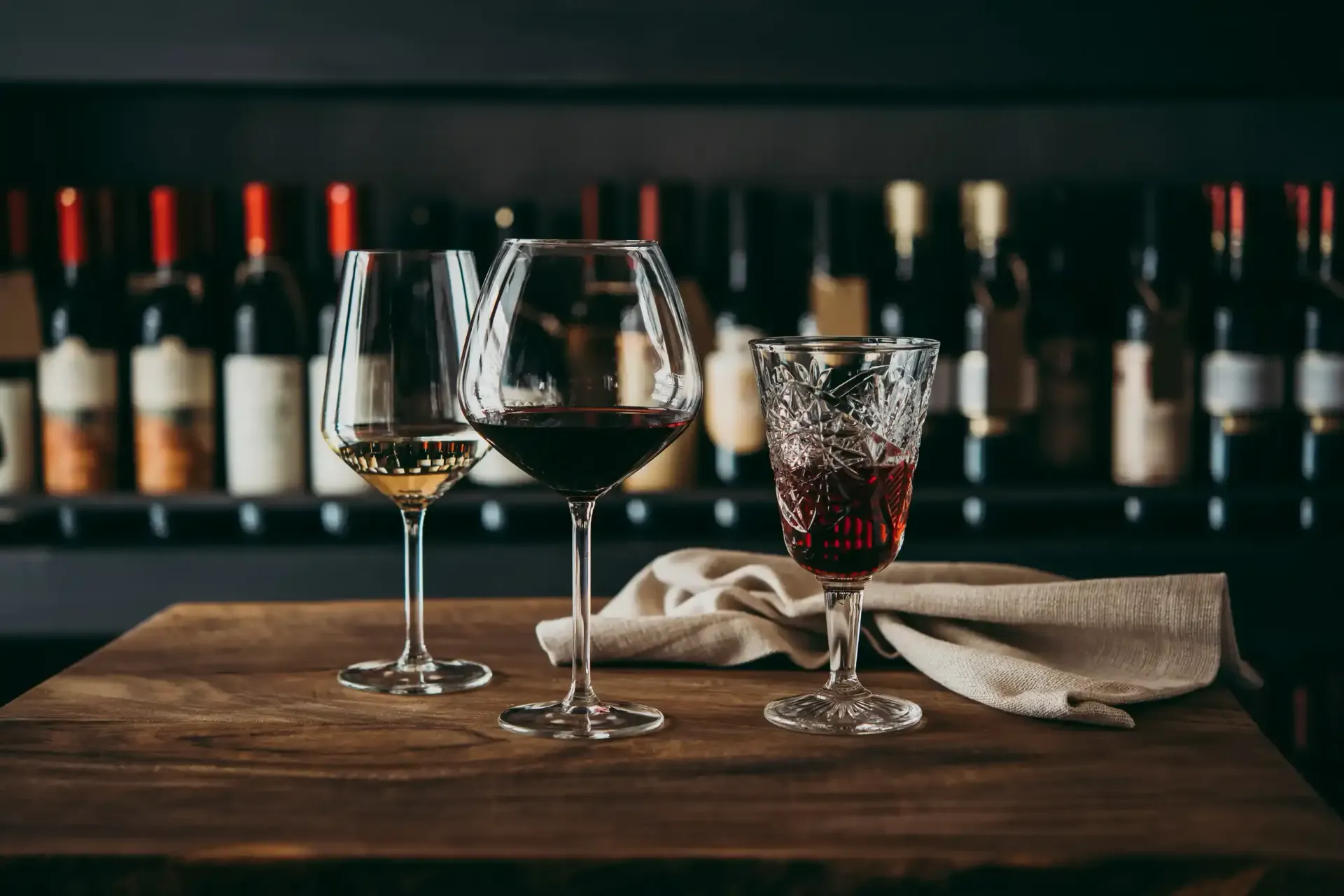 Tres copas de vino están sentadas en una mesa de madera.