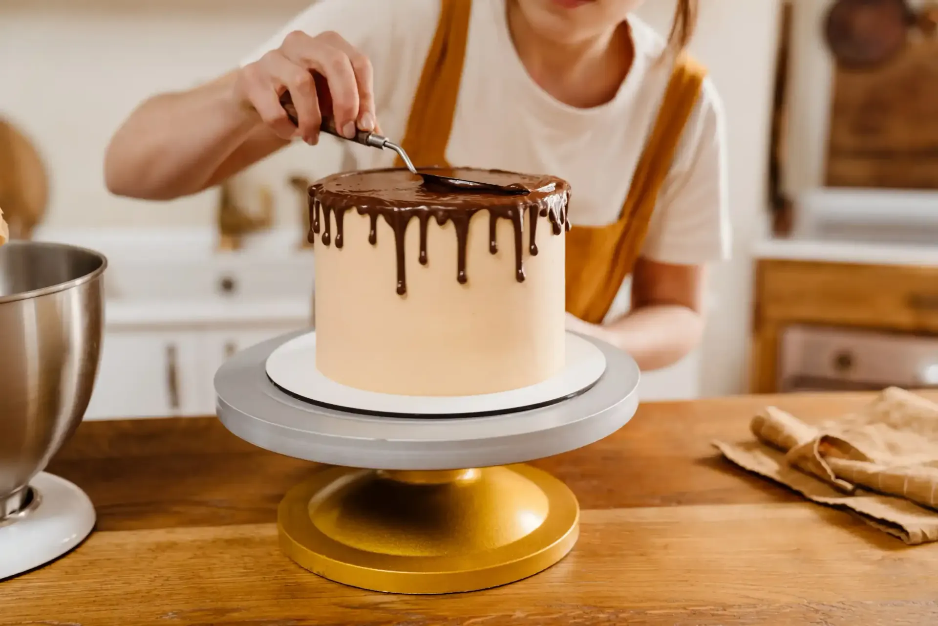 Una mujer está decorando un pastel con glaseado de chocolate.