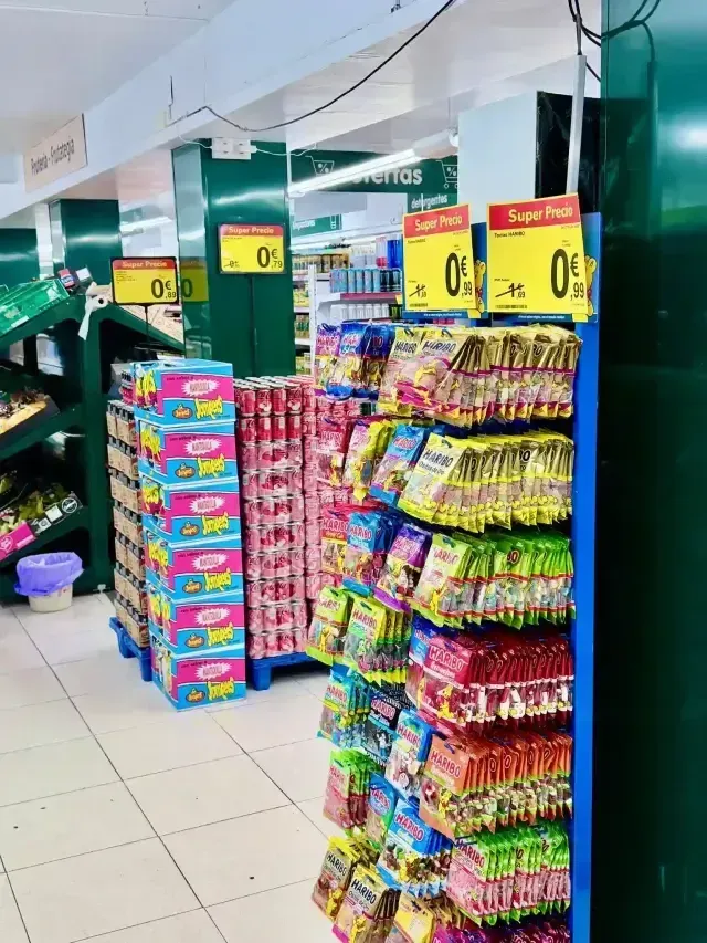 Un pasillo de supermercado con coloridas exhibiciones de bocadillos y dulces envasados en estantes de metal azul.