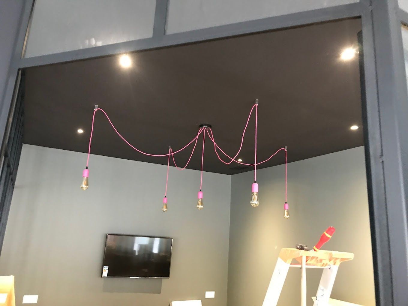 Pose d'un vaste luminaire aux câbles roses dans un salon