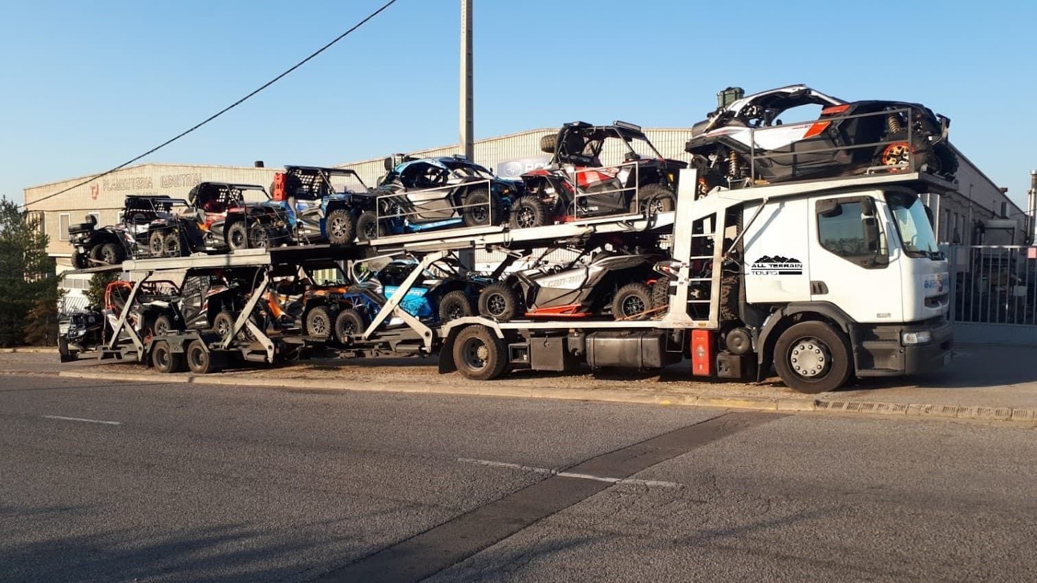 Camión cargado de quads en un día soleado.