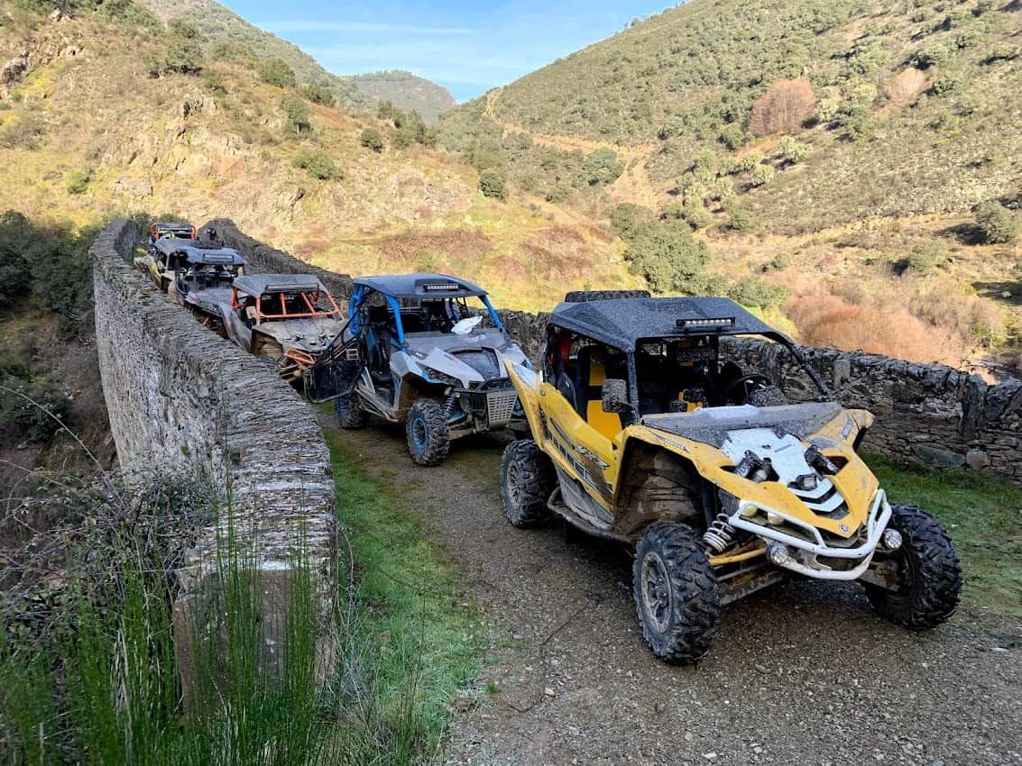 Los vehículos todoterreno se alinean sobre un puente de piedra en un entorno montañoso al aire libre.