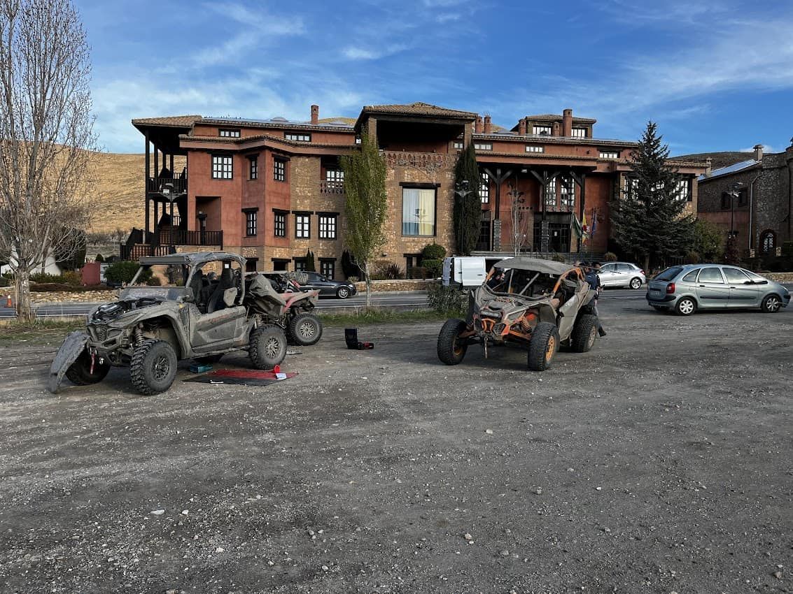 Dos vehículos todoterreno dañados en un terreno de grava frente a un edificio de ladrillo de varios pisos.