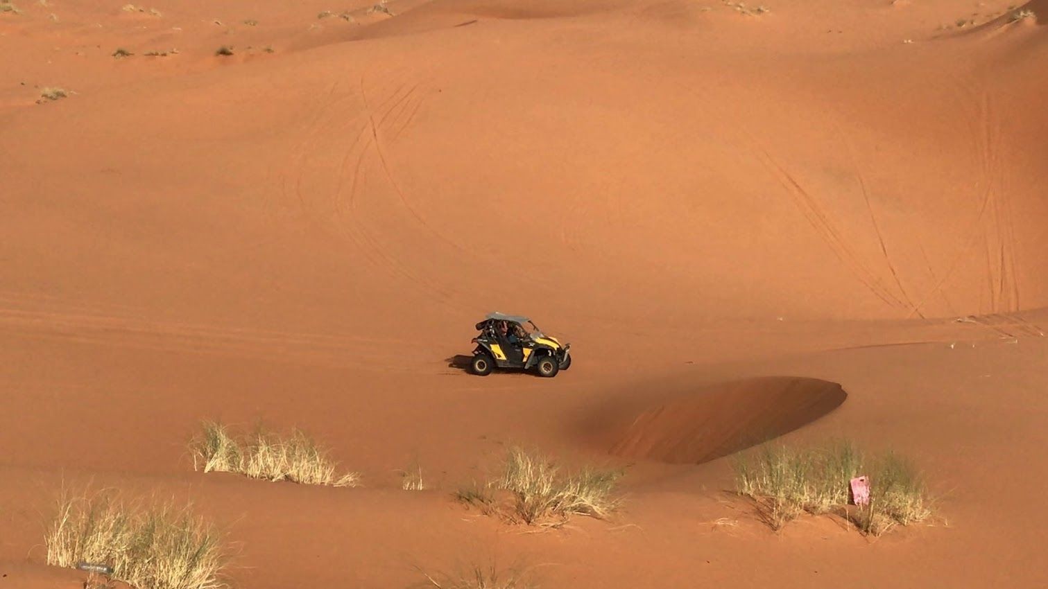 Conducción de quad a través de un vasto desierto de dunas de arena naranja.