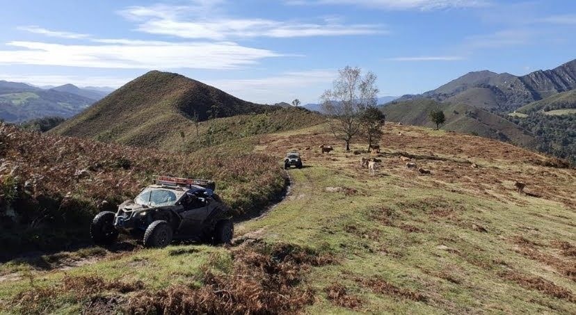 Dos vehículos todoterreno circulan por un sendero de cresta de montaña en un día soleado.