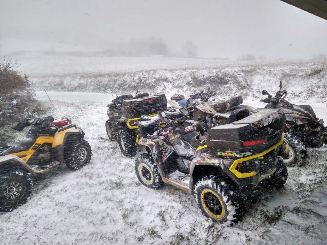 Cuatrimotos estacionadas en suelo nevado cerca de un campo en un día nublado.