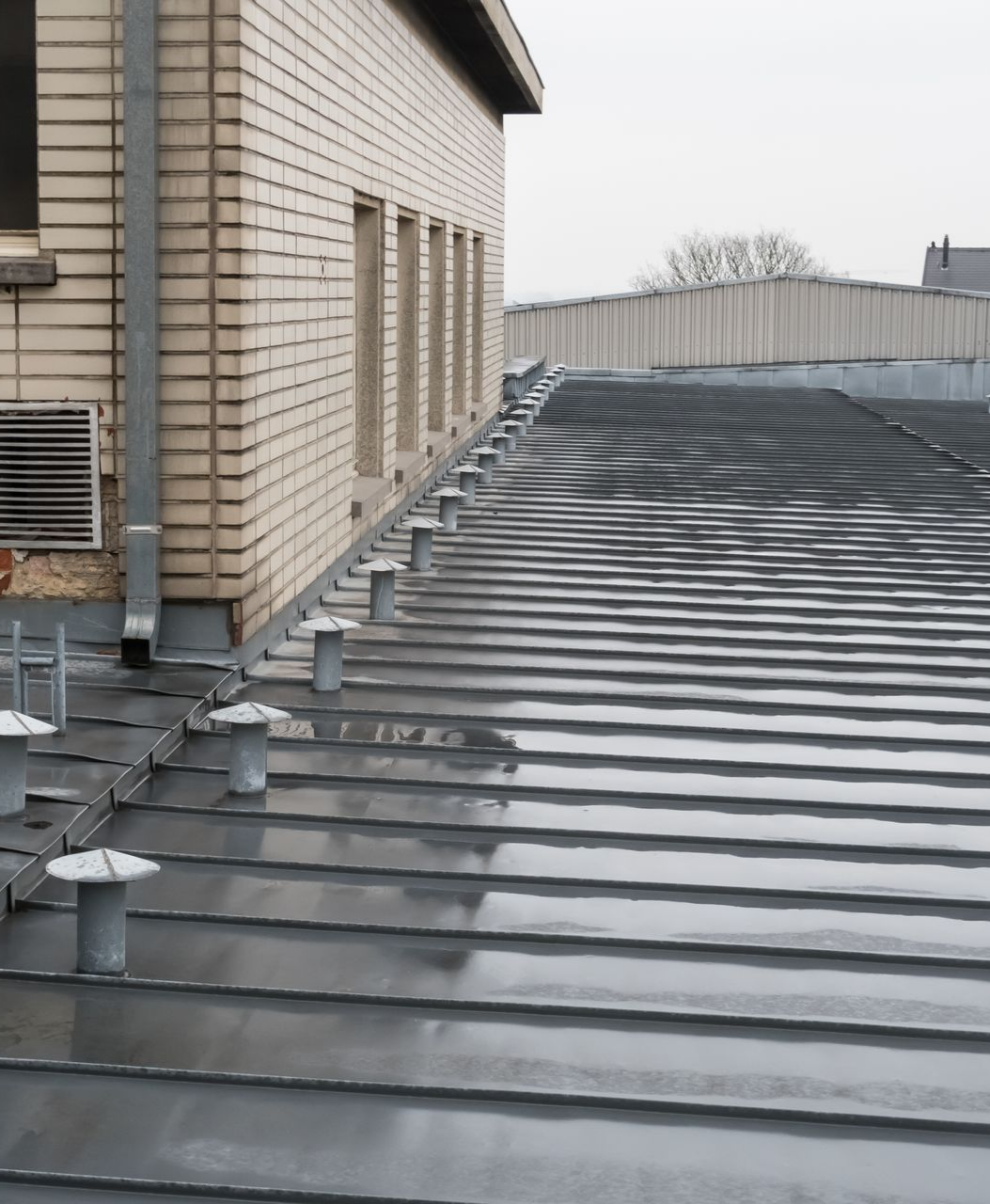 Une toiture en métal jouxtant un bâtiment en briques.