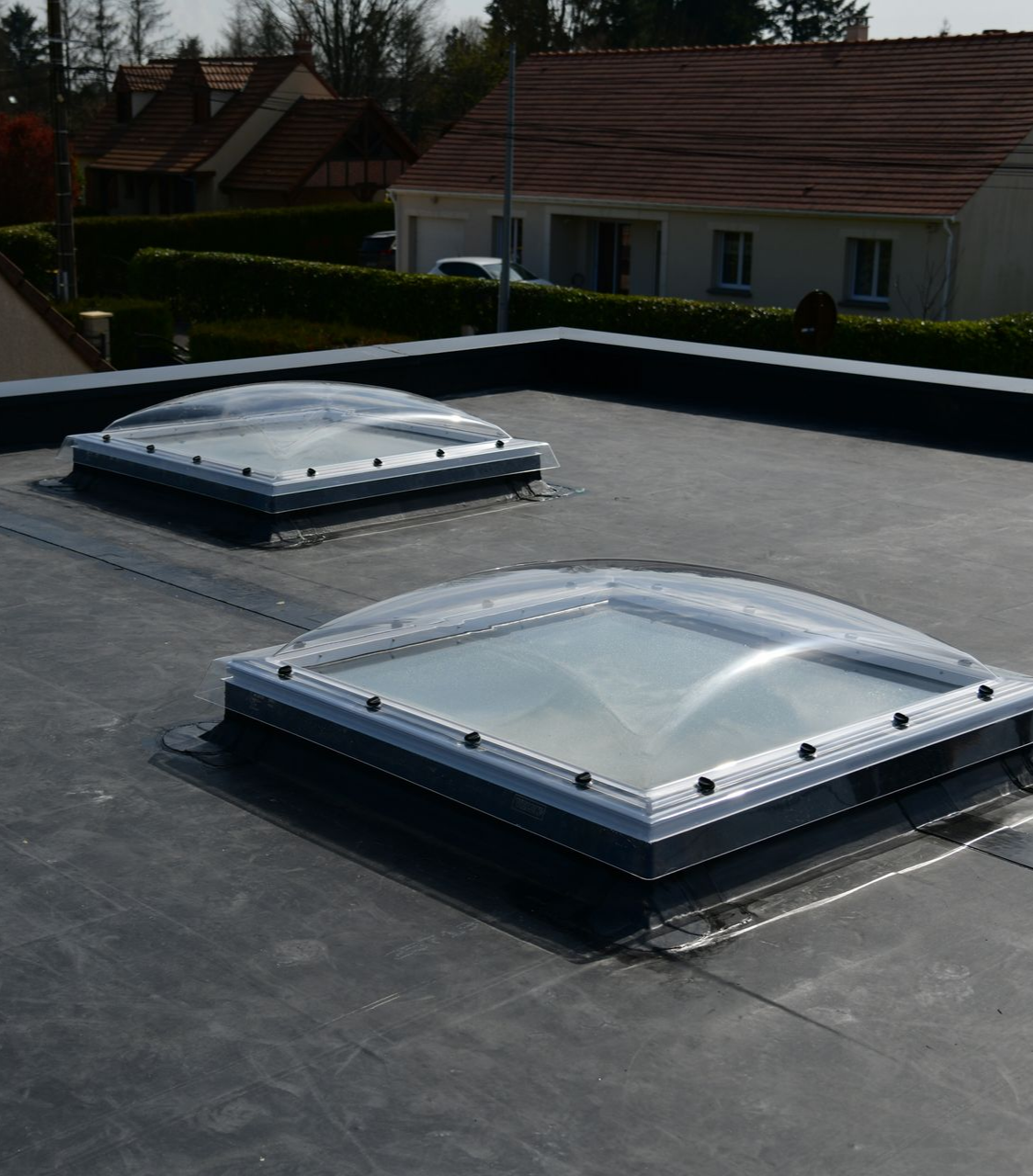 Deux puits de lumière en forme de dôme sur un toit-terrasse.