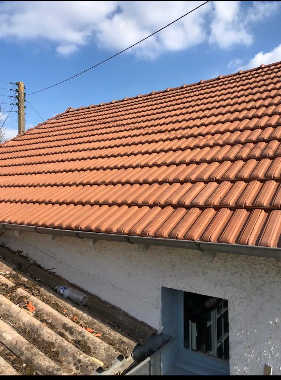 Toit en tuiles rouges, ciel bleu en arrière-plan.