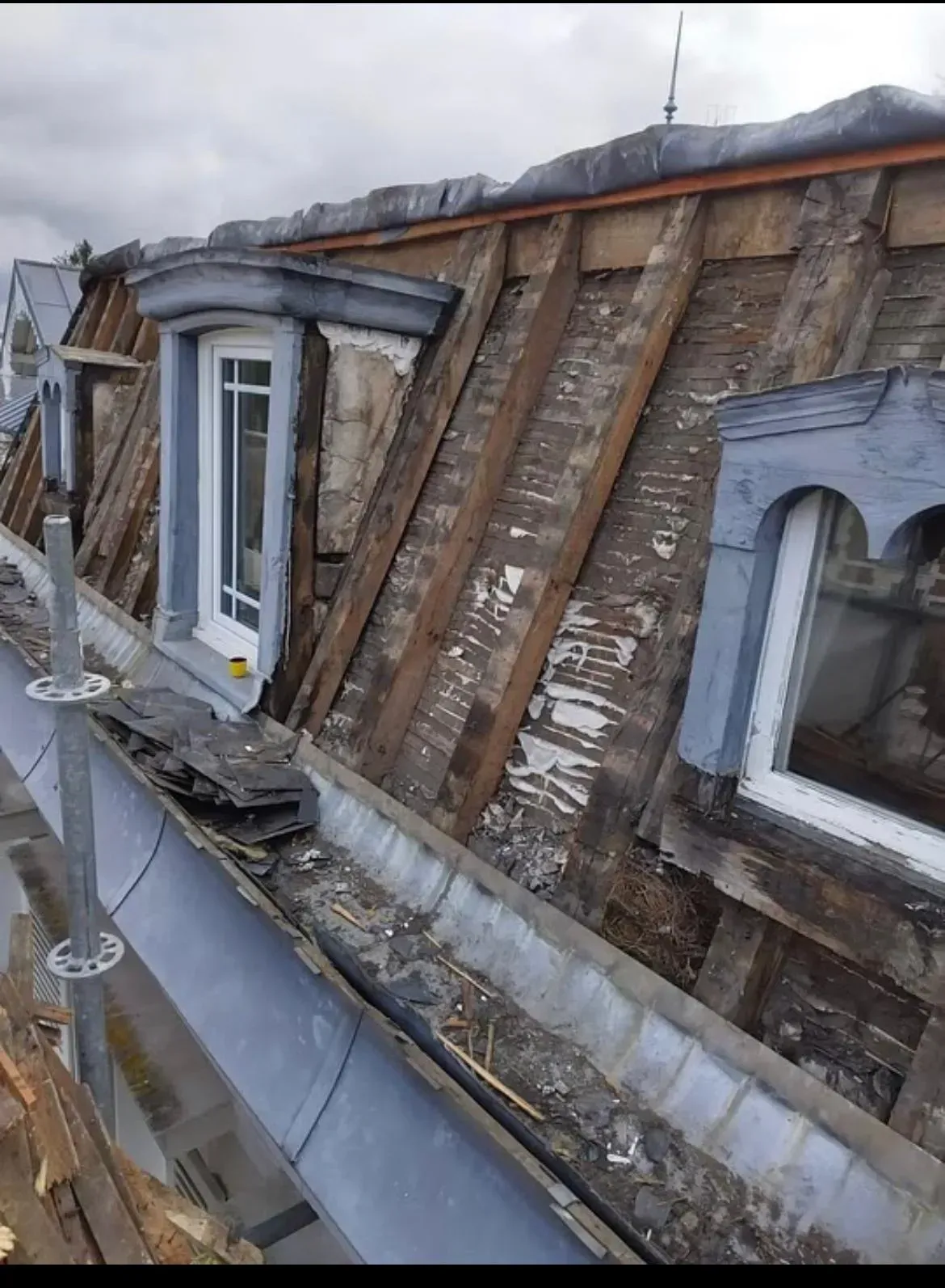 Toiture en cours de rénovation, avec poutres apparentes et lucarnes.