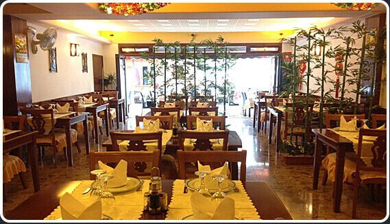 Un restaurante lleno de mesas y sillas con platos y vasos sobre ellas.